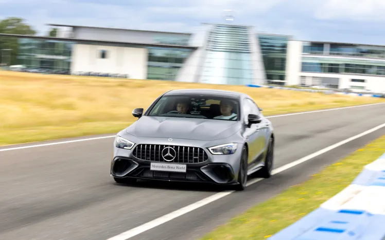 A high-performance Mercedes-AMG car speeding on a racetrack at Mercedes-Benz World, demonstrating dynamic driving capabilities.