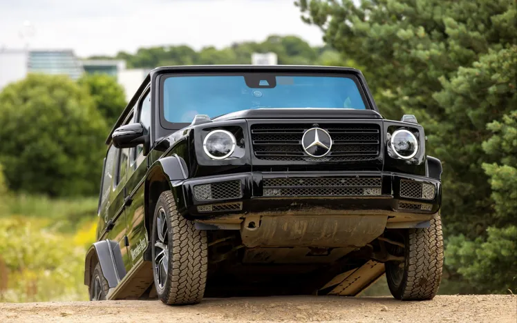 Passenger enjoying a thrilling 4x4 ride through rugged terrain at Mercedes-Benz World's Off-Road Circuit, showcasing vehicle capability and adventure.